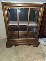 Front view of wooden display cabinet base with glass door and shelf