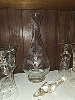 Decanter centered with etched design, surrounding glasses partially visible