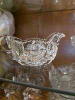 Clear cut glass creamer showing sawtooth rim and starburst cuts