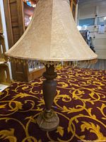 Full view of cast-iron table lamp with beaded fringe shade