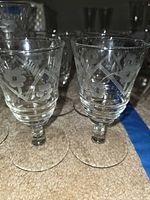 Group of shorter juice glasses showing etched floral pattern and stems