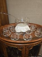 Entire punch bowl set arranged on surface: bowl, ladle, twelve cups