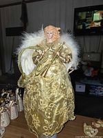 Full view of gold angel tree topper standing on table