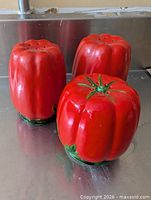 Front view of three red tomato ceramic shakers