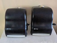 Front view of both black San Jamar dispensers side by side