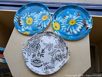 All three plastic trays laid out: two blue daisy print, one white black floral print