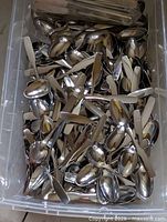 Plastic bin filled with small stainless steel spoons