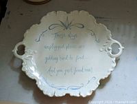 Front view of ceramic platter showing full design, handles, scalloped edges, and quote