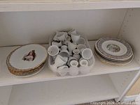 stacked portrait plates, tub of white egg cups, additional plate stack on shelf