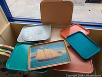 Group of six assorted plastic trays showing colors and sizes
