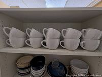 Shelf view showing eight matching stoneware mugs stacked in pairs