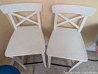 Front view of both white bar stools showing X-back design and seats