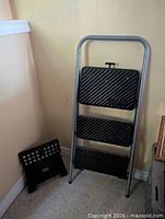 Both step stools leaning against wall