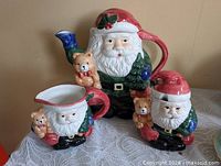 Front view of all three Santa Claus ceramic pieces: teapot, creamer, sugar bowl