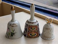Three ceramic handbells side by side showing overall designs
