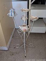 full view wrought iron plant stand with ceramic teapots attached