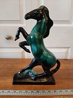 Left side view of 14-inch green and black drip-glaze rearing horse figurine displayed beside ruler