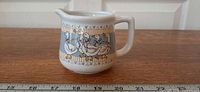 Front view of creamer showing Ribbon Geese motif and scale