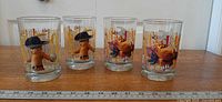 Four Puss in Boots collector glasses front graphic shown with ruler for length