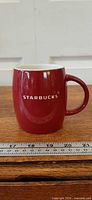 Front view of red Starbucks mug with ruler indicating size