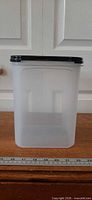Front view of container showing frosted body and black seal lid, ruler at base