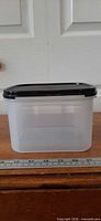 Front view of clear square container with black lid