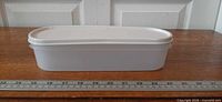 Side view of white Tupperware Modular Mates Oval #1 with lid