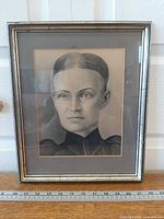 Full view of framed charcoal portrait with ruler for scale