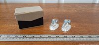Overall view showing both glass booties beside gift box and ruler for scale