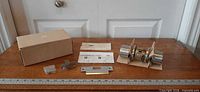 All components laid out: lockset, latch, strike plate, screws, instructions, box, against ruler for scale