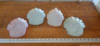 Four pastel iridescent cupcake plates aligned with ruler