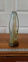 Front view of green and brown swirl art glass vase showing basket-form lobes and coloration