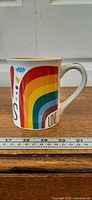 Left side of mug showing rainbow graphic and measurement scale