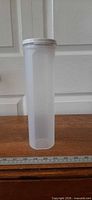 Full view of 11" Tupperware spaghetti keeper showing clear body and white lid next to ruler