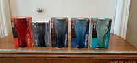Front view of all five boxed glasses aligned with ruler