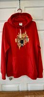 Front view of red Crooks & Castles hoodie hanging