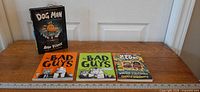 All four books laid out with ruler for scale