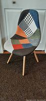 Front-left view of accent chair showing patchwork fabric and wood legs