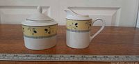 Front view of sugar bowl with lid and creamer pitcher showing pattern