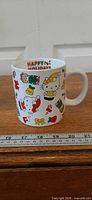 Front view of white ceramic mug showing Happy Holidays text and holiday graphics