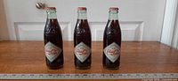 Front view of three sealed 250 ml Coca-Cola commemorative bottles