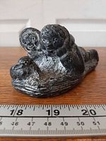 Front three-quarter view of Wolf Original Inuit figures with rabbit sculpture beside ruler