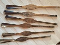 All six seafood picks laid out showing both fork and scoop ends and center motifs