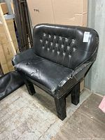 Front angle of black vinyl buggy seat bench showing diamond-tufted back and steel leg frame