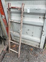 Full view of ladder leaning against metal wall