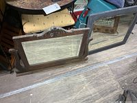 Brown ornate mirror and black rectangular mirror side by side