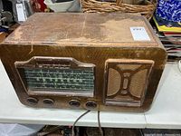Front view of General Electric wood radio showing dial, buttons, knobs, speaker grille