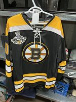 Front view of Reebok Boston Bruins jersey hanging on rack