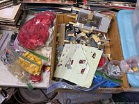 Cardboard box with grey plate assemblies, instruction sheet, assorted parts and adjoining bags of coloured Lego bricks