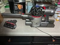 Vacuum on charging dock with crevice tool attached and motorized brush beside